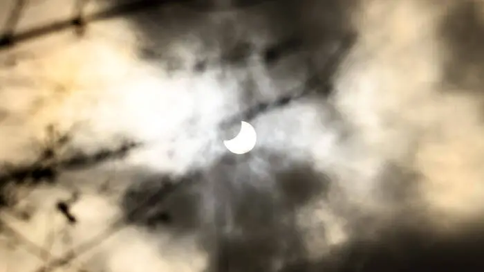 Das Bild zeigt eine partielle Sonnenfinsternis die leicht von Wolken verdeckt wird