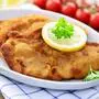 Auf einem Teller liegen zwei Wiener Schnitzel, garniert mit einer Zitronenscheibe | „Burgi‘s Dorfküche“ bietet unter anderem Wiener Schnitzel (ausschließlich zum Mitnehmen) an