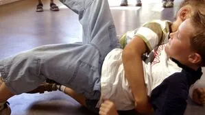 Zwei Kinder raufen am Gang in einem Schulgebäube