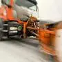 Ein oranger Schneepflug räumt Schnee von der Straße  | Unfall beim Schneeräumen 