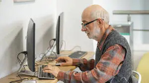 Senior man working on computer at desk. Focused senior man working on computer at desk. model released