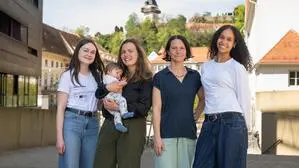 Vier Frauen stehen in einer Gruppe zusammen, eine hält ein Baby, im Hintergrund ist in der Ferne der Uhrturm zu sehen