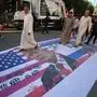 Iraqis step on a flag of the US bearing the portrait of US President Donald Trump during a march in the Kadhimiya district of Baghdad on June 21, 2025, to protest against Israel's strikes on Iran. (Photo by AHMAD AL-RUBAYE / AFP)