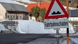 Ein Schild weist auf die Fahrbahnschäden hin