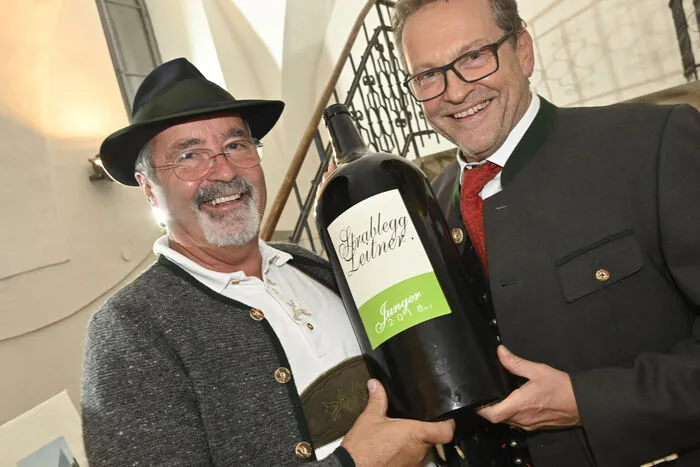 Hubert Franz mit Josef Pleikner präsentieren jungen Wein in einer Magnumflasche.
