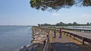 Ein Radweg mit zwei Radfahrern und eine Straße in einer Lagune am Meer