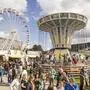 Übersichtsfoto eines Volksfestes mit zahllosen Menschen, einem Riesenrad und einem Ringelspiel darauf
