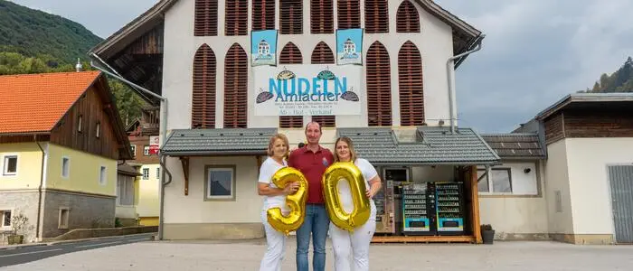 Zwei Frauen und ein Mann stehen vor einem Gebäude
