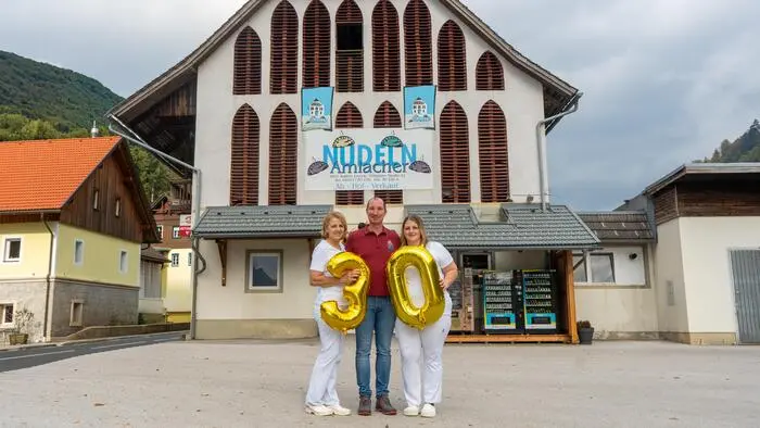 Zwei Frauen und ein Mann stehen vor einem Gebäude