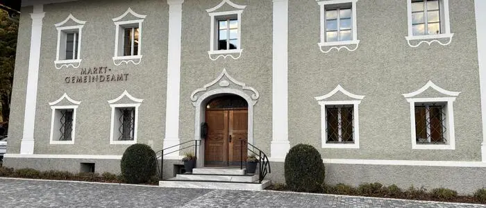Ein historisches Verwaltungsgebäude mit verzierten Fenstern und einer großen Holzeingangstüre