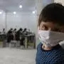 Erst der Krieg, dann Corona: ein Bub in der umkämpften nordsyrischen Stadt Idlib. Im Hintergrund werden Atemschutzmasken genäht 