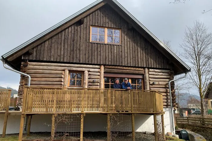 Hans und Marianne Wechselberger auf der Veranda des Stallgebäudes, das vom rund 300 Jahre alten Originalholz umhüllt ist