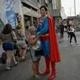 TOPSHOT - Leonardo Muylaert, 36, known as the Brazilian Superman, poses for a picture with a woman at the Saens Pena Square in the Tijuca neighborhood in Rio de Janeiro, Brazil, on March 18, 2024. Muylaert, a lawyer who didn’t have social media one year ago, found out a video of him visiting an event went viral on TikTok, calling him the "Brazilian Superman." He liked the idea and jumped on a Superman costume, and since then, he has been traveling around Brazil as Superman. (Photo by MAURO PIMENTEL / AFP)