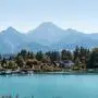 Blick auf einen türkisblauen See, dahinter Bäume und Berge am Horizont