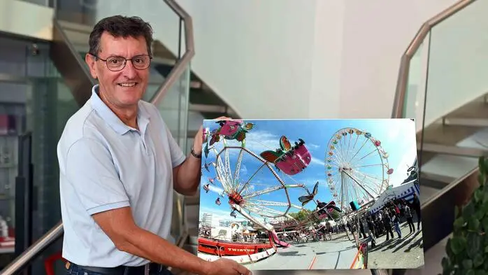 Ein Mann hält ein Bild in der Hand. Darauf zu sehen ist der St. Veiter Wiesenmarkt.