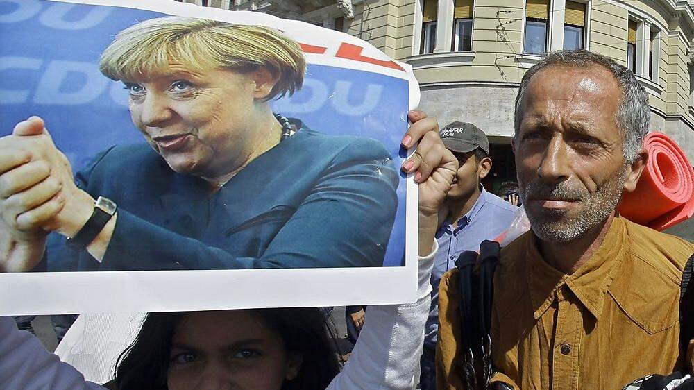 Ein Migrant hält ein Foto Merkels hoch 