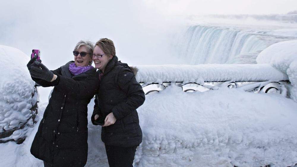 Touristen vor den teilweise vereisten Niagara-Fällensi