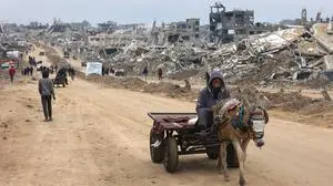 A man rides a donkey-pulled cart past the rubble of destroyed buildings at Saftawi street in Jabalia, in the northern Gaza Strip, on February 5, 2025 during a ceasefire deal in the war between Israel and Hamas. Palestinian militant group Hamas lashed out on February 5, at President Donald Trump's shock proposal for the United States to take over the Gaza Strip and resettle its people in other countries, seemingly whether they want to leave or not. (Photo by Omar AL-QATTAA / AFP)