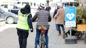 Eine Dame am Fahrrad, die gerade von einer Mitarbeiterin in Warnweste ans Absteigen erinnert wird