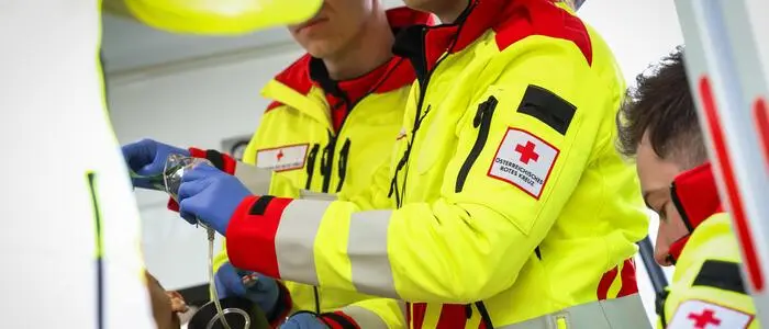 Mehrere Rotkreuz-Sanitäter stehen bei einem Patienten im Rettungswagen