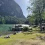 Ein See, auf der Wiese davor liegen einige Menschen