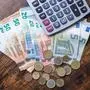 Euro banknotes and coins are on the table with a calculator.