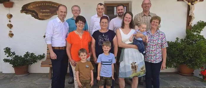 Eine Gruppe von Personen steht vor einem Bauernhaus