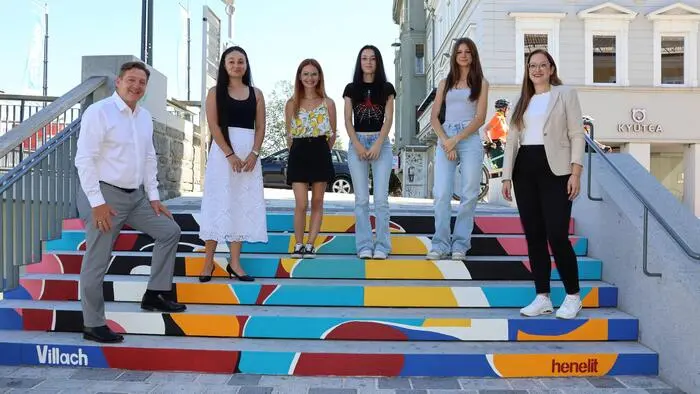 Eine Gruppe mit sechs Menschen steht auf einer bunt bemalten Treppe