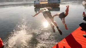 Man sieht zwei Personen wagemutig in den Wörthersee springen, dahinter sieht man eine schwimmende Plattform | Manche konnten es kaum erwarten, endlich ins kalte Wasser zu springen