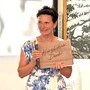Eine Dame mit kurzen schwarzen Haaren hält ein Schild mit der Aufschrift „Herzlichen Dank“ in Händen