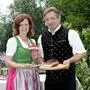 Jutta und Johannes Lassnig von der gleichnamigen Buschenschank im Ort Terpetzen. Sie tragen Tracht, Johannes hält auf einem Jausenbrettl ein Stück Speck, Jutta die dazugehörige Auszeichnung „Speckkrone“ in den Händen