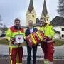Drei Männer, zwei Sanitäter und der Bürgermeister, stehen mit Erste-Hilfe-Ausrüstungen vor der Pfarrkirche Diex |  Hannes Topar, Bürgermeister Anton Napetschnig und Thomas Kummer