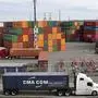 FILE - In this Oct. 2, 2019, file photo trucks hauling shipping containers drive near containers stacked five-high at a terminal on Harbor Island in Seattle. Defying fears and predictions, the American job market is still shrugging off President Donald Trump’s trade wars. Employers added an impressive 266,000 jobs in November, and unemployment returned to a 50-year low 3.5% _ all at a time when the Trump administration is engaged in a bruising trade war with China while fighting other U.S. trading partners as well.(AP Photo/Elaine Thompson, File)
