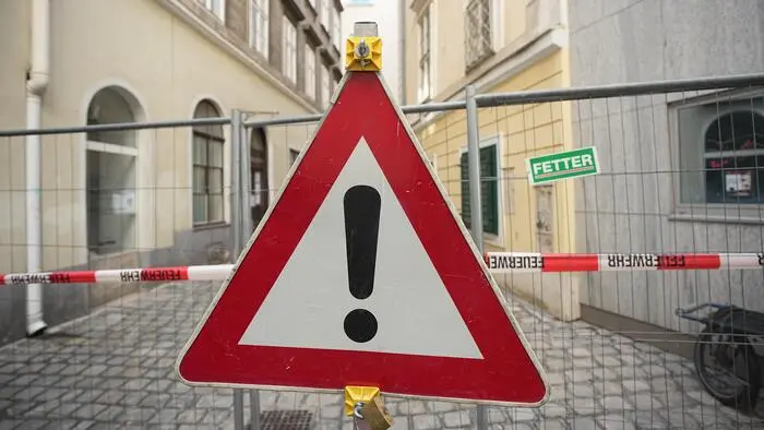 Warnschild an Absperrungszaun in der Wiener Innenstadt.