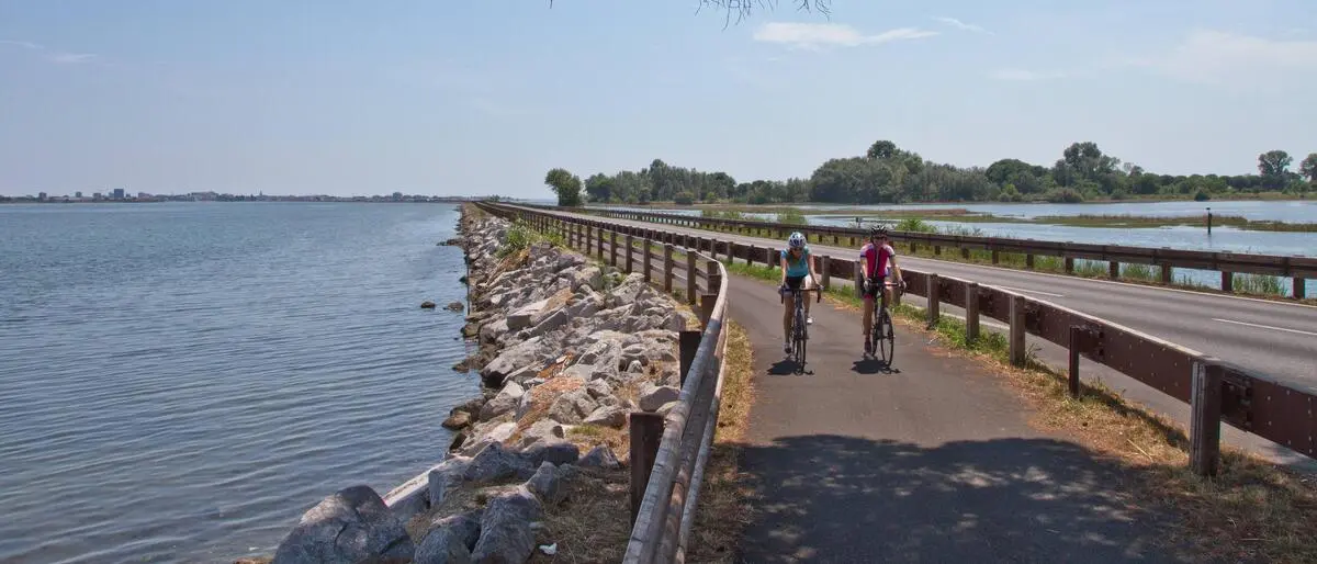 Ein Radweg mit zwei Radfahrern und eine Straße in einer Lagune am Meer