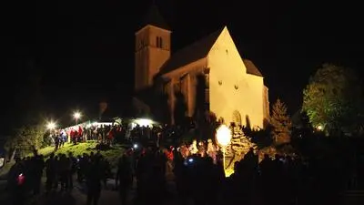 Eine beleuchtete Kirche bei Dunkelheit mit Pilgern 