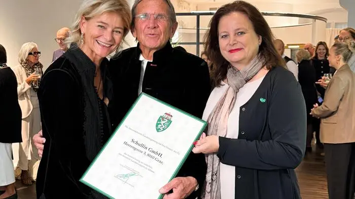 Die drei Personen zeigen stolz die Urkunde zur Führung des Landeswappens