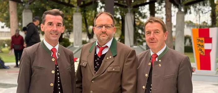 Drei Politiker blicken in die Kamera. Sie haben traditionelles Kärntner Gewand an.
