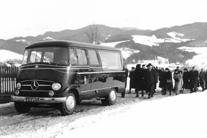 Bestattungsauto vor einem Trauerzug (1960er-Jahre)