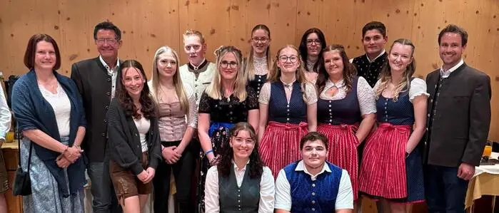 Mehrere Personen in Tracht haben sich in einem Speisesaal zu einem Gruppenfoto drapiert