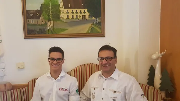 Franz Perschler mit Sohn Lukas, im Hintergrund ein Bild des Traditionshauses in seinen Anfängen.