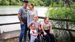 Emily mit ihren Schwestern und ihren Eltern. Der Rollstuhl hält das lebensfrohe Mädchen nicht auf