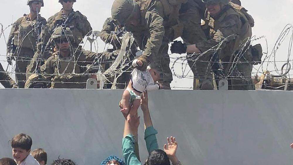 Ein Soldat packte das Baby am rechten Arm und reichte es an Kollegen weiter