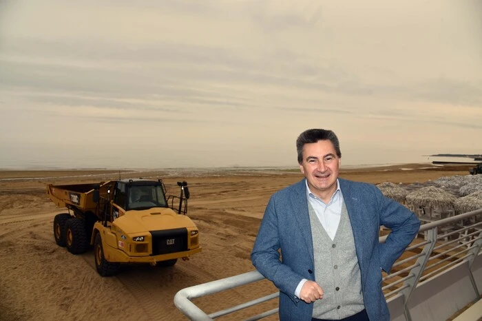 Giorgio Ardito von der Lignano Pineta Betreibergesellschaft, die den Strand von Lignano Pineta betreibt am Strand von Lignano Pineta vor einem der Laster, die den von den Meereswellen vom Strand  weggespülten Sand jetzt vom Leuchtturm Faro Rosso wieder zum Strand von Lignano Pineta zurückführen. 