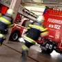 Feuerwehrmänner rennen zu Einsatzfahrzeugen