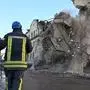 Ukrainian rescuers supervise the dismantling of a residential building partially destroyed as a result of a missile attack in Kharkiv on January 17, 2024. At least 17 people were wounded in Russian strikes on residential buildings in the city centre on January 16, 2024, the regional governor said. (Photo by SERGEY BOBOK / AFP)