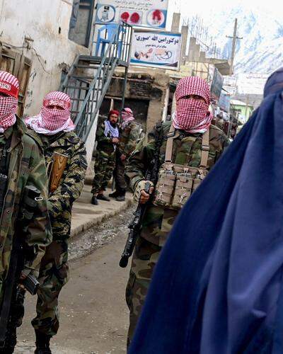 Taliban-Kämpfer stehen hinter einer Frau mit Burka | Seit 2021 wird Afghanistan wieder von den radikalen Taliban beherrscht.