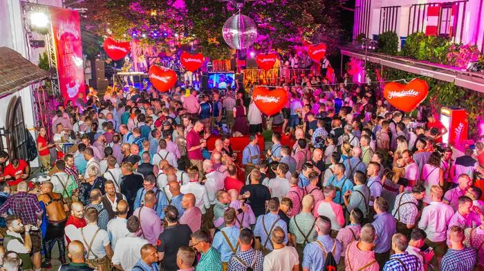 Eine große Party von oben fotografiert. Viele tragen Tracht und es hängen Herzen in der Luft