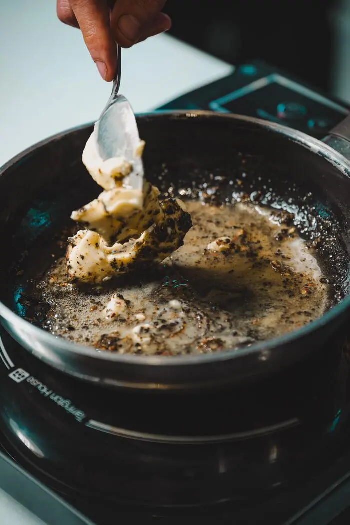 Die konfierten Hühnerflügel werden durch die feine Soße gezogen.