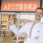 Ein Mann mit weißem Kittel deutet auf ein Schild mit der Aufschrift „Apotheke“ | Sebastian Blaschitz hat die „Apotheke Wernberg“ übernommen